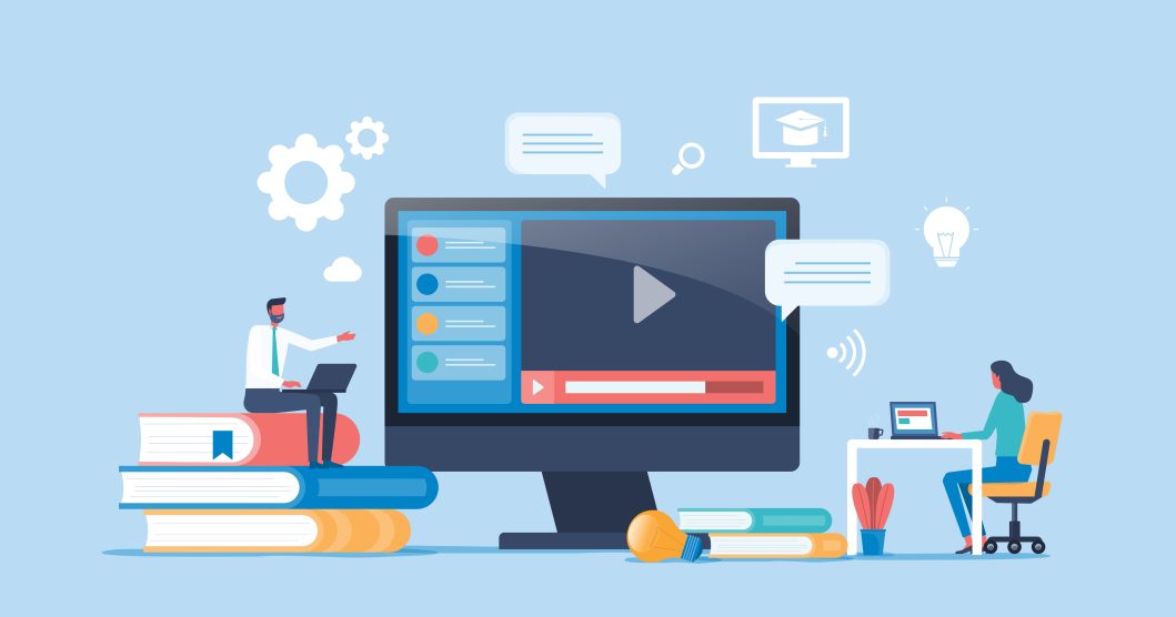 Man sitting on books, woman at desk with laptop, large computer screen displaying video play button.