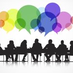 Silhouetted group of people in meeting with colorful speech bubbles above their heads.