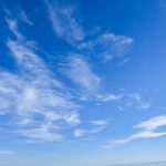 Blue sky with scattered wispy white clouds on a clear sunny day.