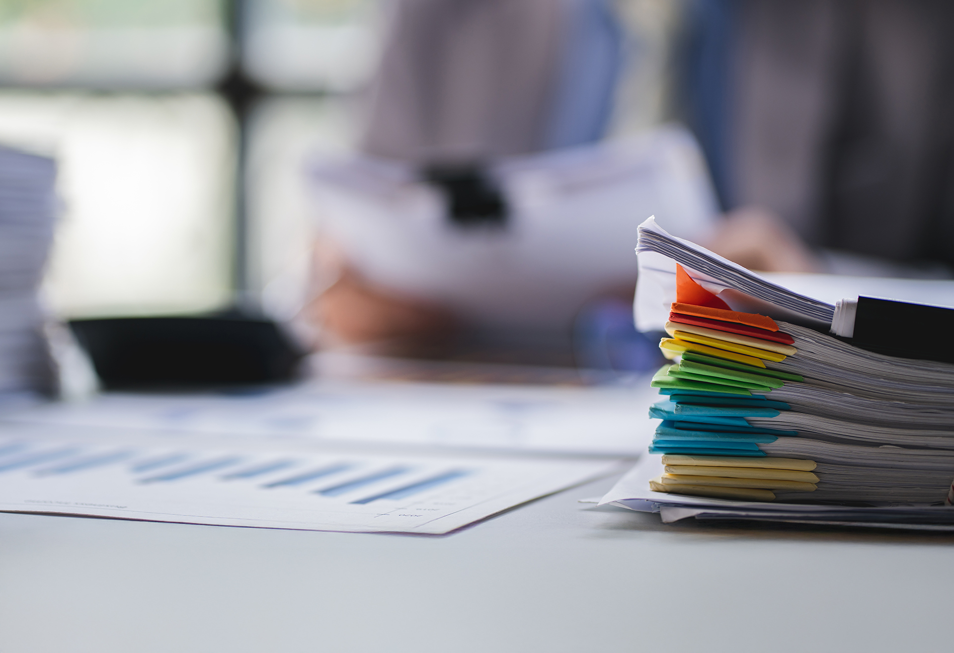 A stack of paperwork with multi-colored stickers on top of a table