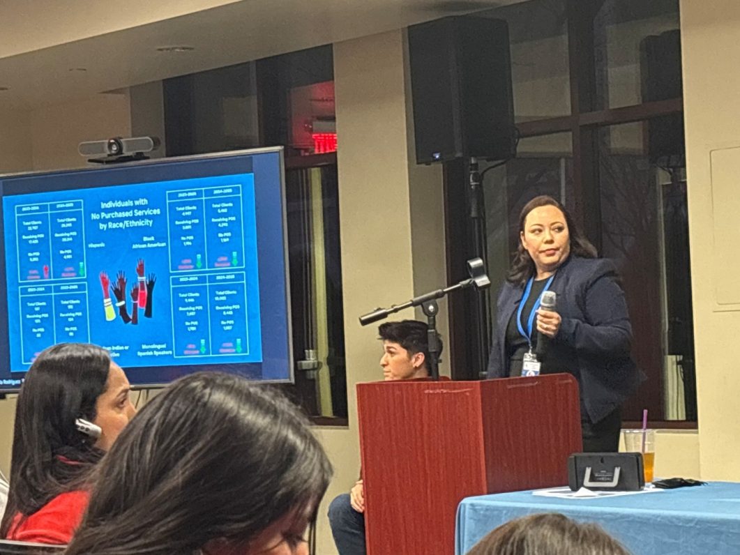 A person is presenting a spreadsheet in front of a podium at a community or family-focused event.