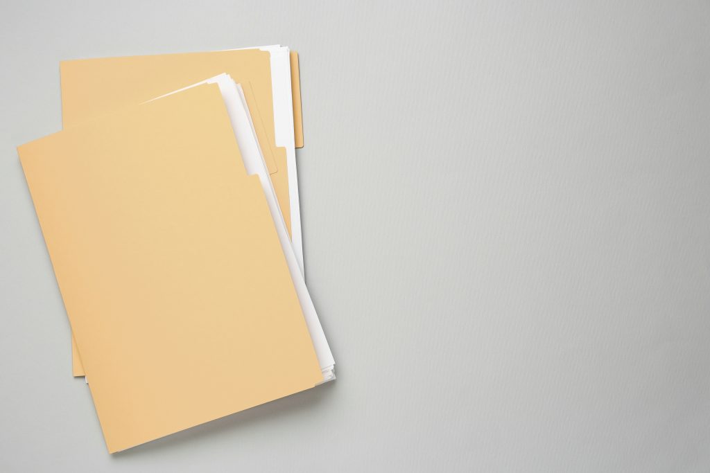 Two manila folders with papers inside on top of a gray surface
