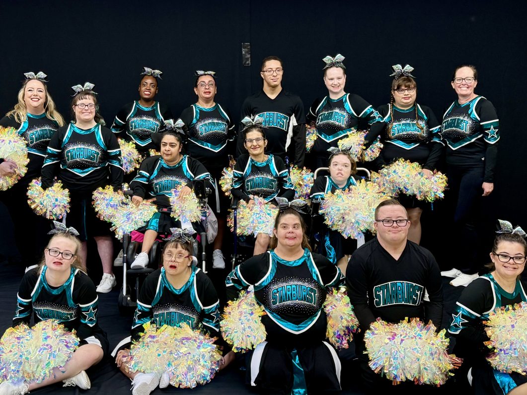 Starburst cheer team formal group photo in black and teal uniforms holding pom-poms.