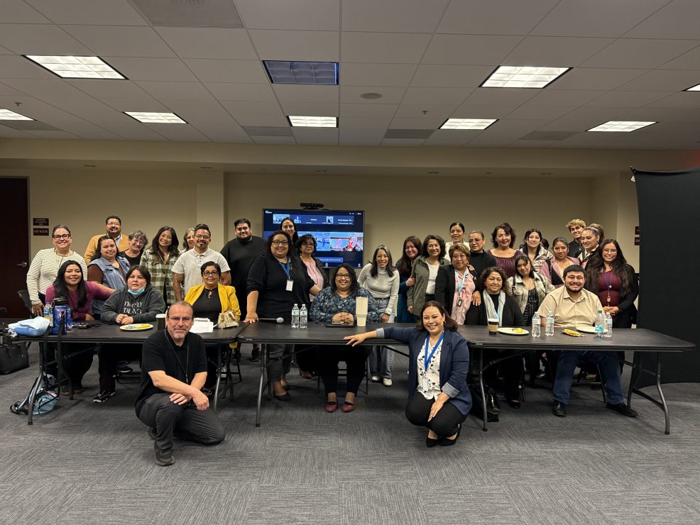 Group photo of panelists and attendees gathered in a conference room during an autism acceptance month event.